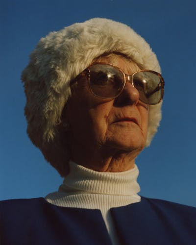 Close-up portrait photo of Niall Hodson's grandmother wearing a fur hat and sunglasses against a blue sky