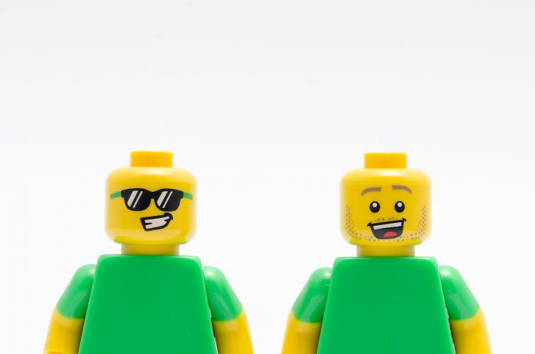 Image shows two smiling LEGO figures wearing green shirts