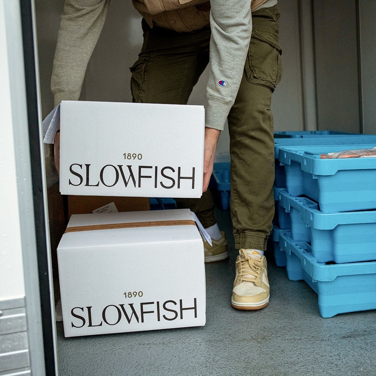 Photograph of a person unloading boxes in a van featuring the Slowfish branding by Vasava on the side