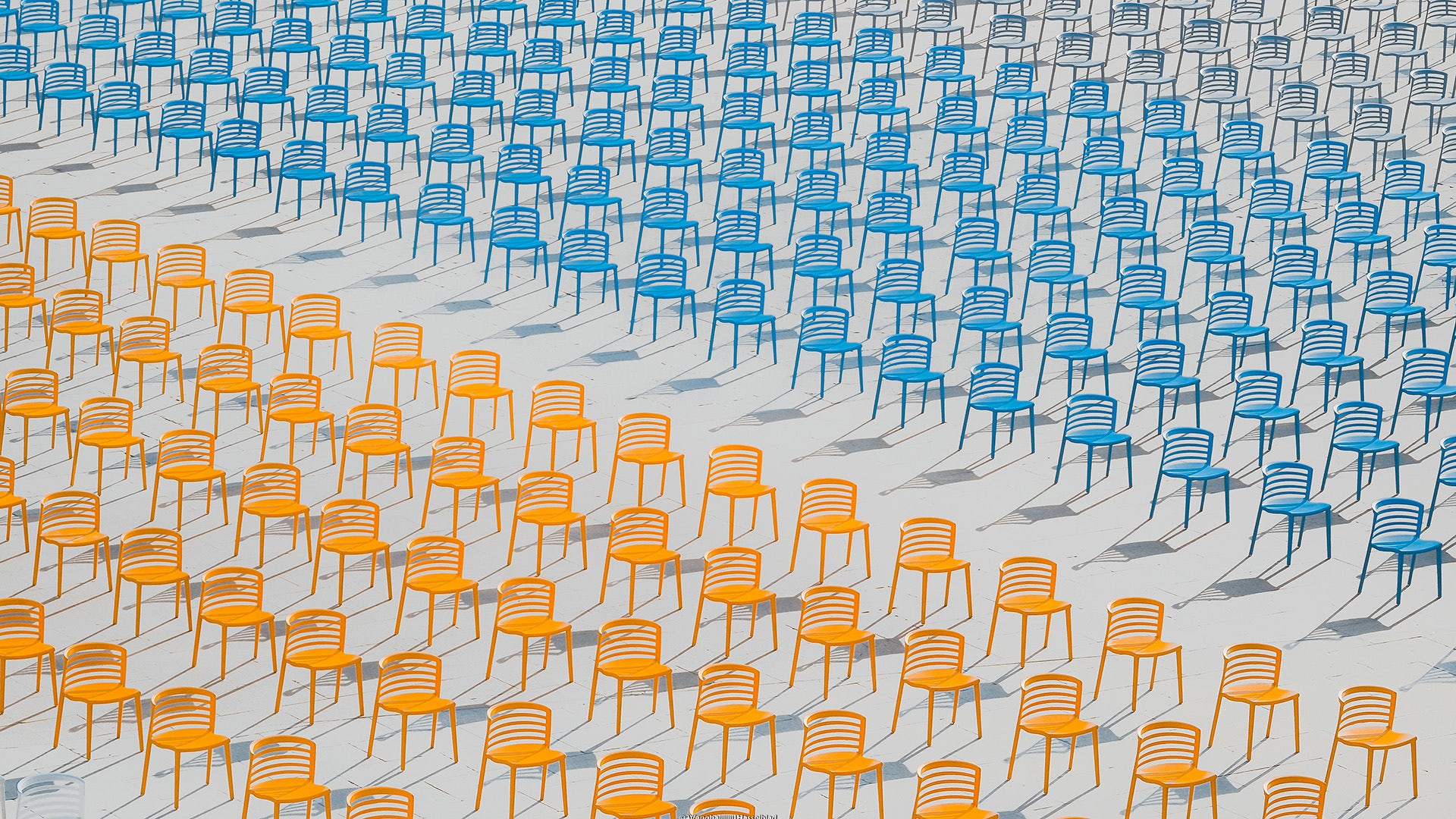 Photograph of rows of orange chairs arranged on the bottom half of the image and rows of blue chairs on the other half, as part of the Sony World Photo Awards 2023